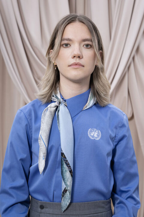 Uniform till guider i FN. blond kvinna med blå skjorta och en skarf knuten runt kragen.