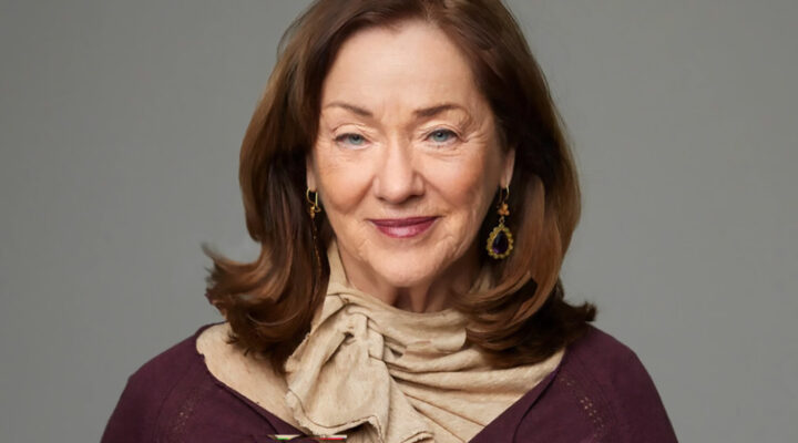 Caj Bond iförd beige scarf och en stickad vinröd tröja.